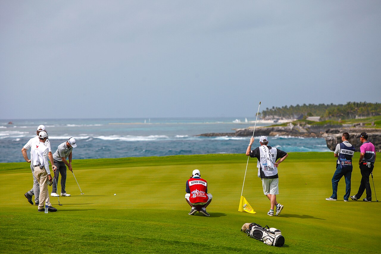 Professional golfers and caddies on a green beside the Caribbean Sea during the Corales Puntacana tournament at Puntacana Resort and Club.