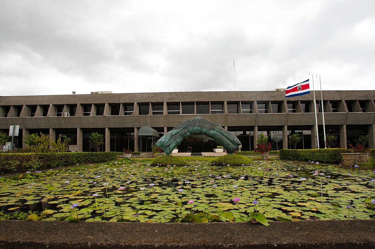 Facade of the Casa Presidencial, the presidential office in San José, Costa Rica, with a lily pond in front and the national flag flying