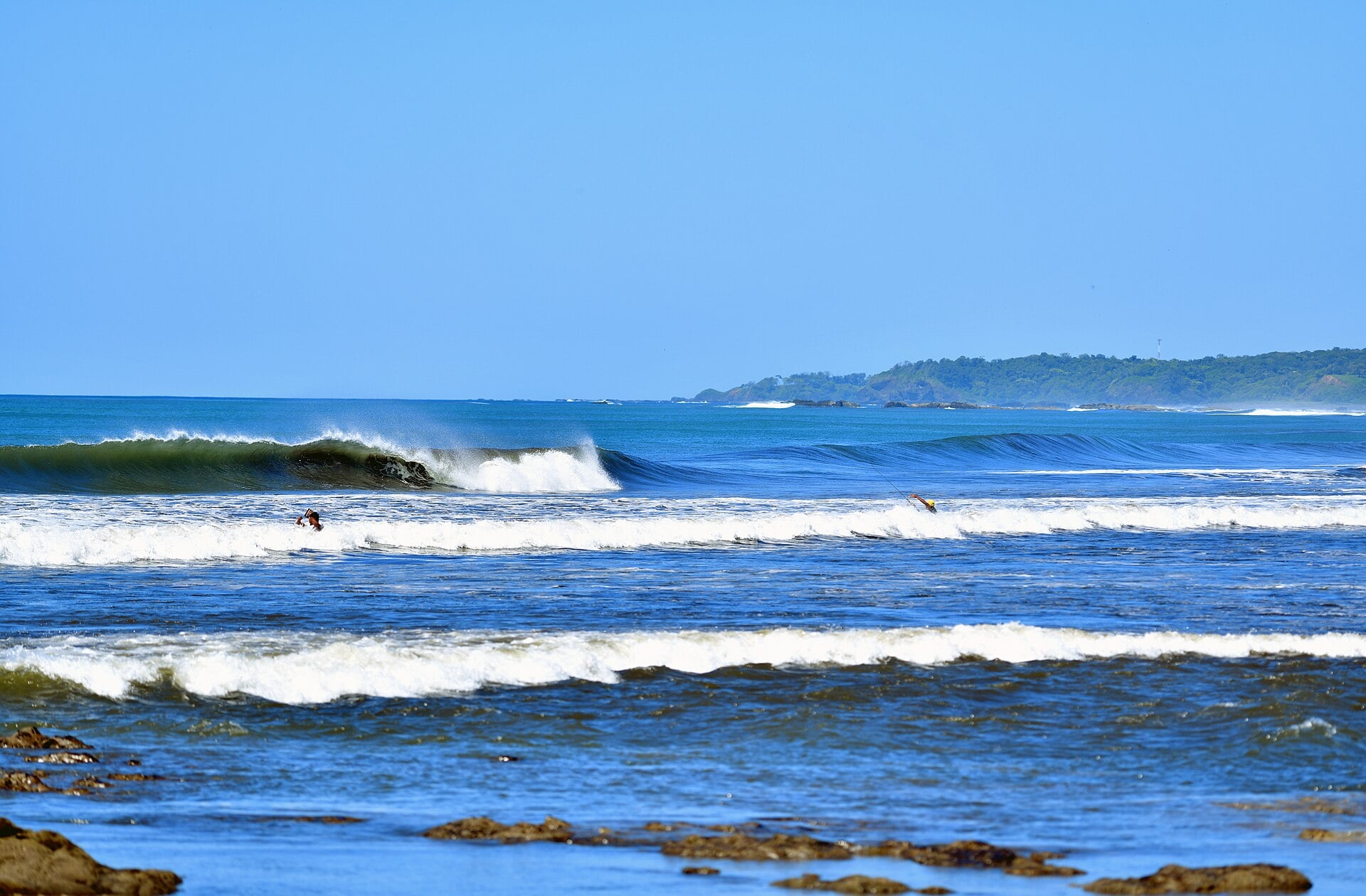 Waves and two people in the surf on the Pacific coast of the Nicoya Peninsula, Costa Rica