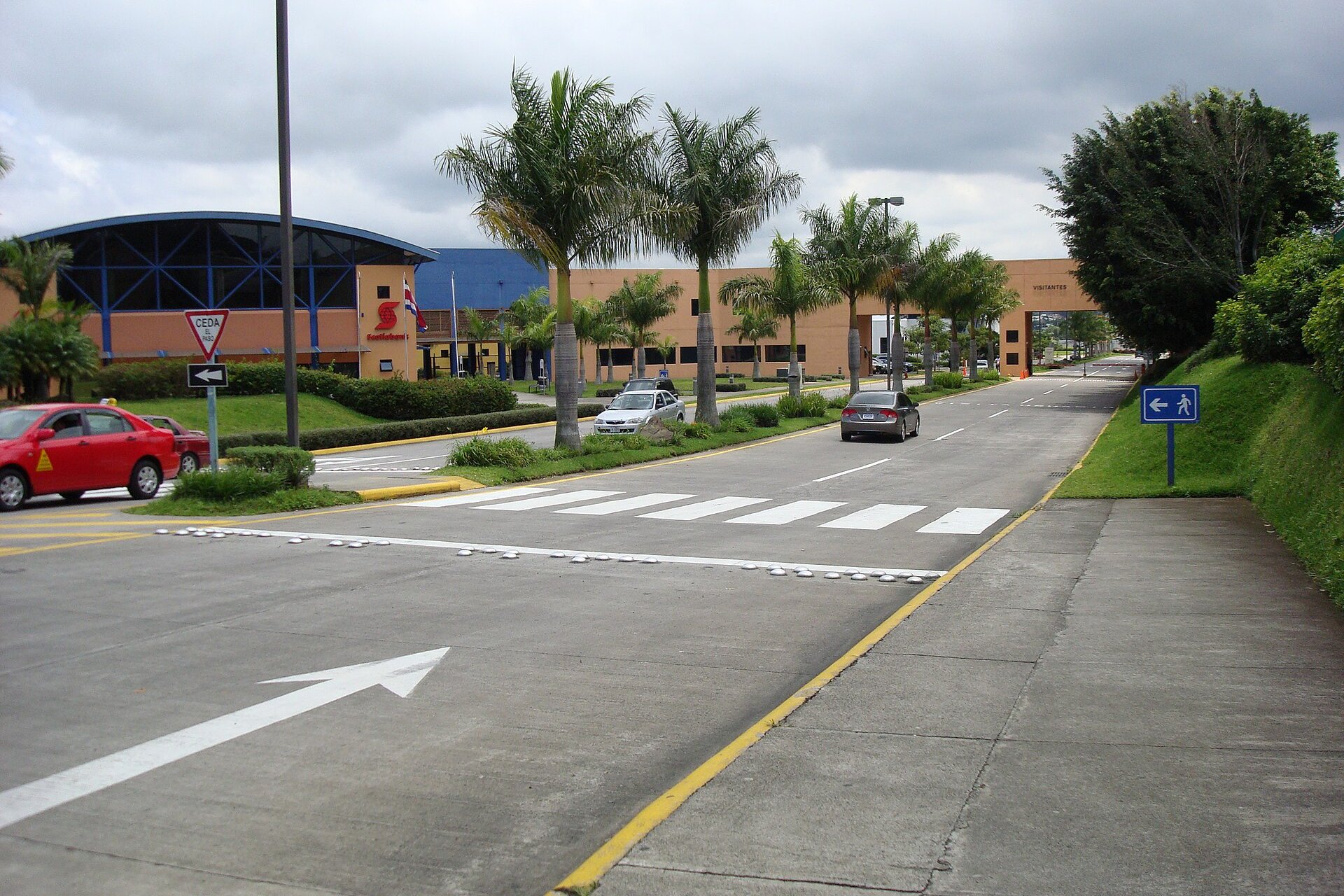 Entrance road and gate of Global Park, a business park in Heredia, Costa Rica, with palm trees and office buildings