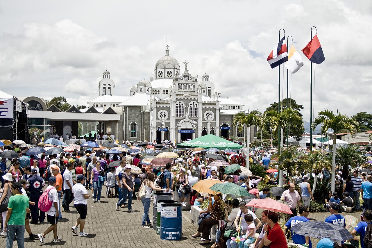 Large crowd with umbrellas on the square in front of the Basilica of Our Lady of the Angels in Cartago during the pilgrimage