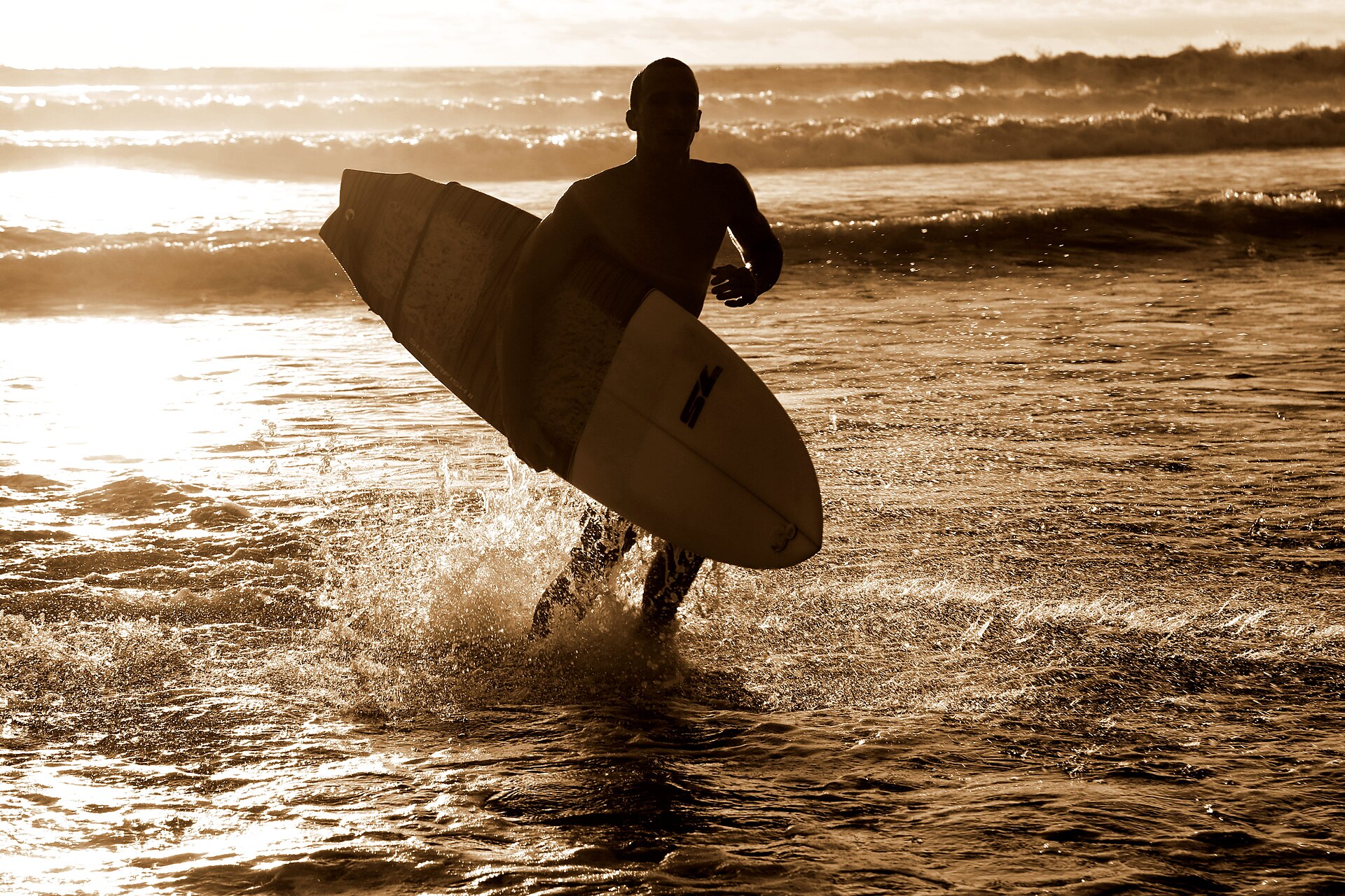 Costa Rica sports: a surfer leaves the water at sunset on the Costa Rican coast