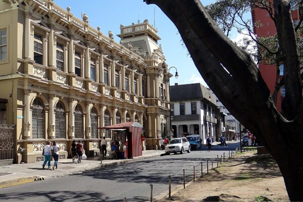 The ornate old main post office building on Avenida 1 in downtown San José, Costa Rica, with pedestrians and a large tree