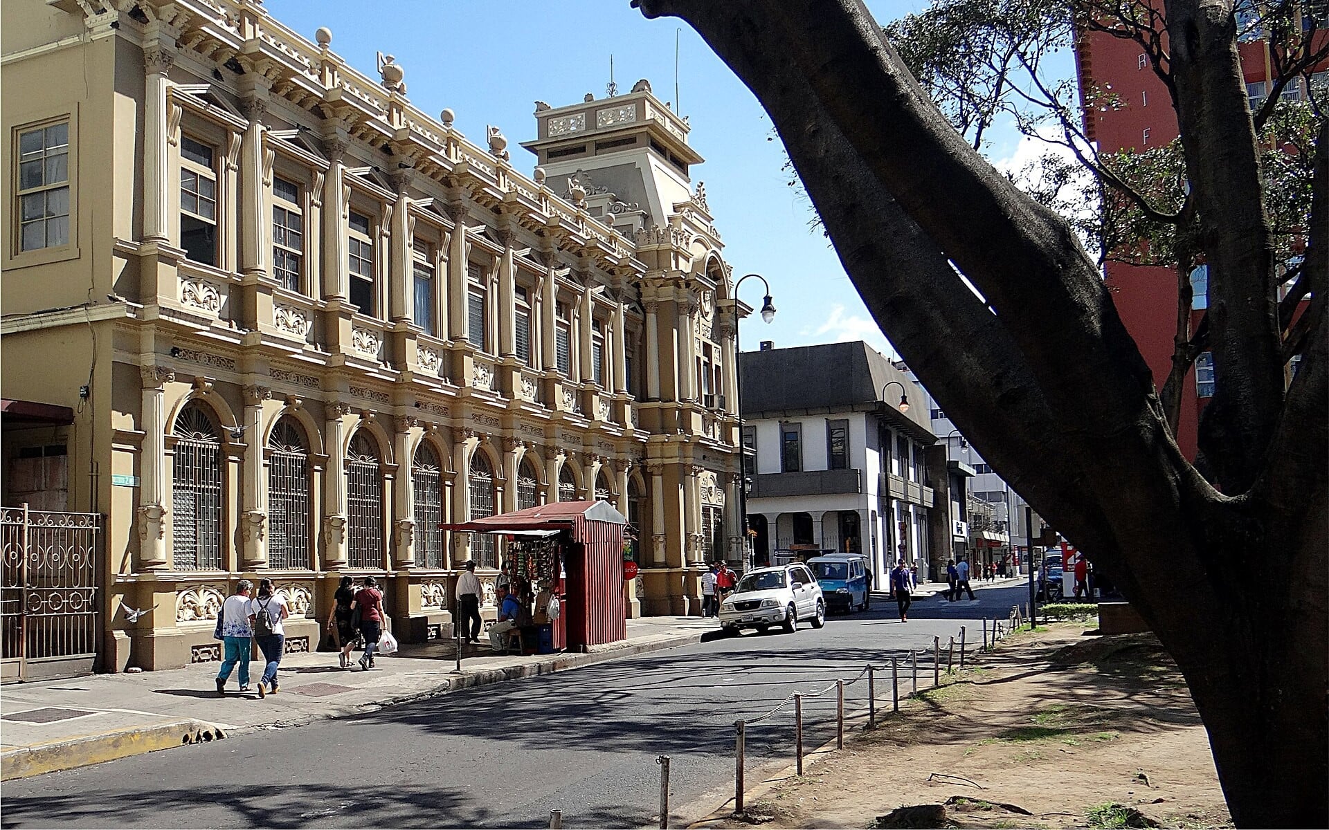 The ornate old main post office building on Avenida 1 in downtown San José, Costa Rica, with pedestrians and a large tree