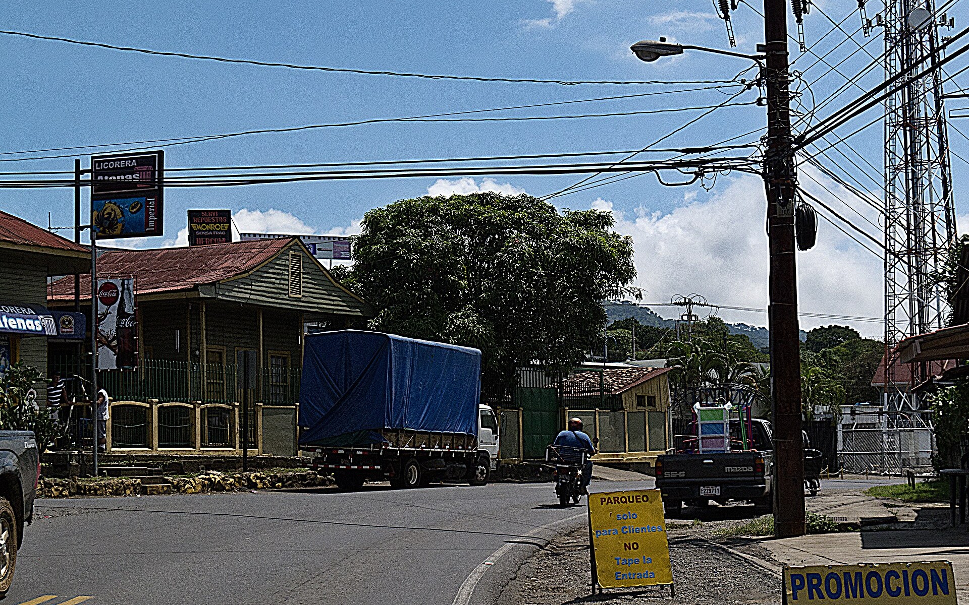 The main street through Atenas, a town in Alajuela province, Costa Rica, with a truck, shops and power lines