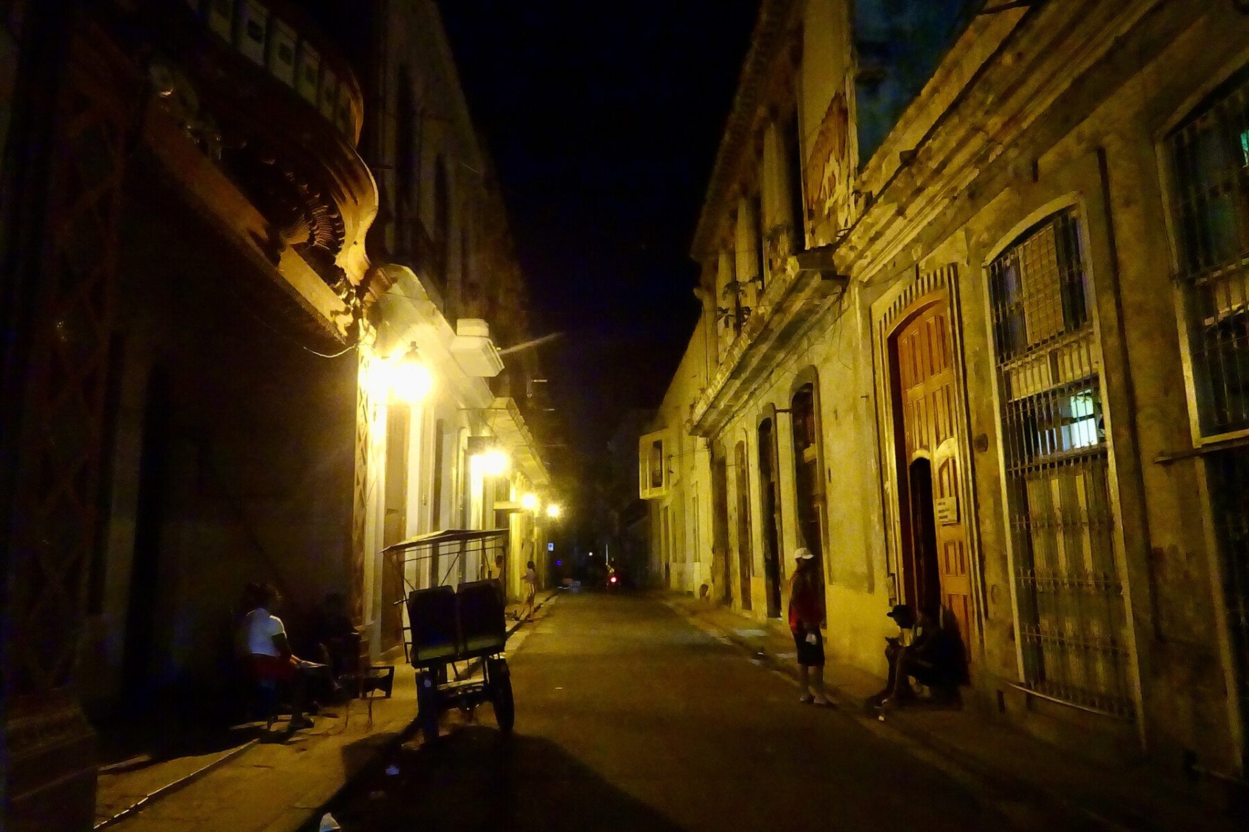 A street in Old Havana at night with a bicycle taxi parked by colonial buildings