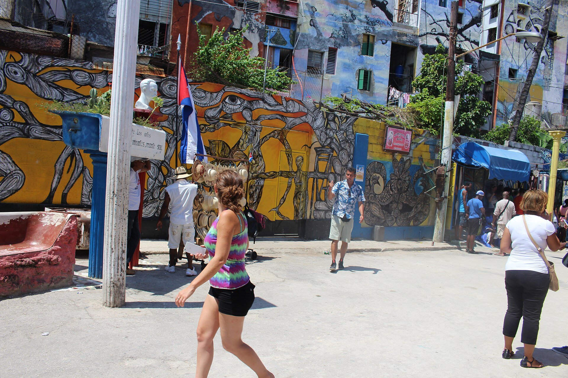 Colourful murals of Afro-Cuban imagery cover the walls of Callejón de Hamel, an alley in Centro Habana, with visitors walking past