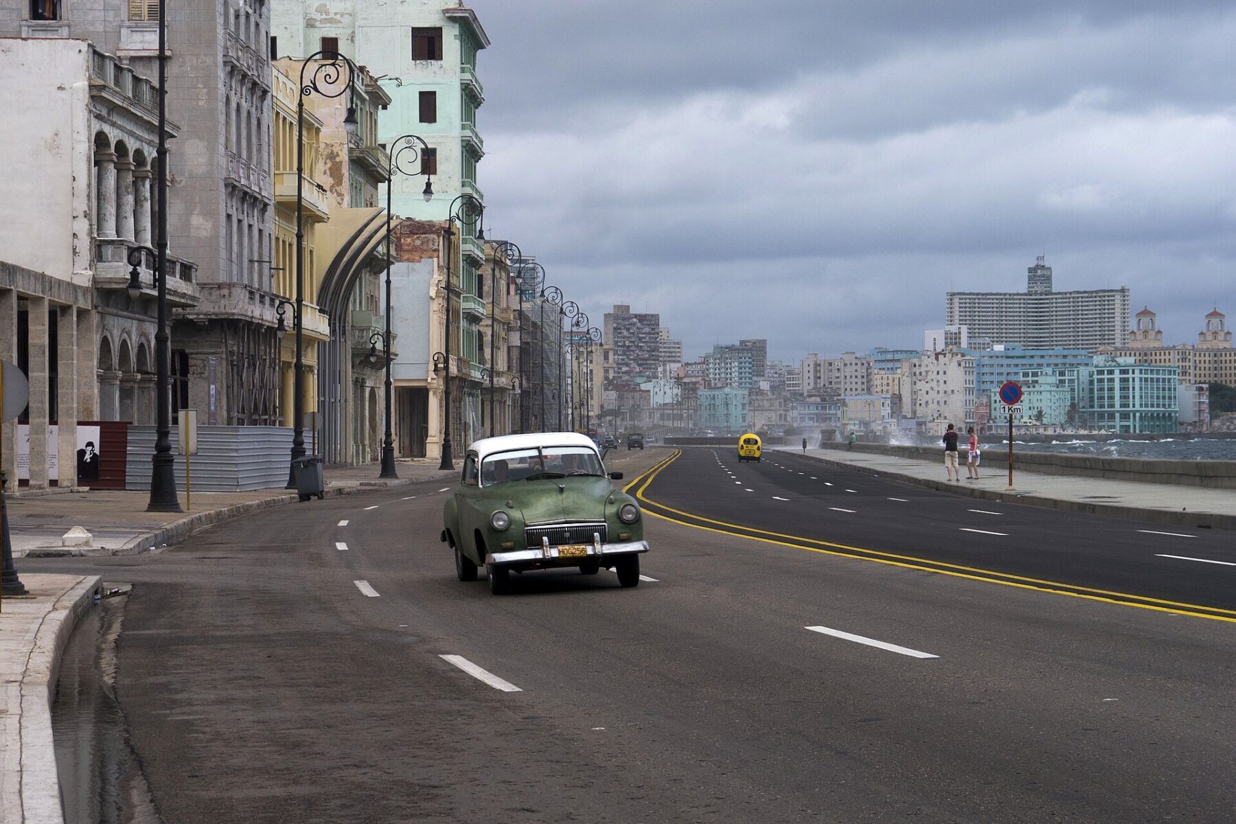 A vintage car drives along the Malecón seafront in Havana, Cuba, under a cloudy sky
