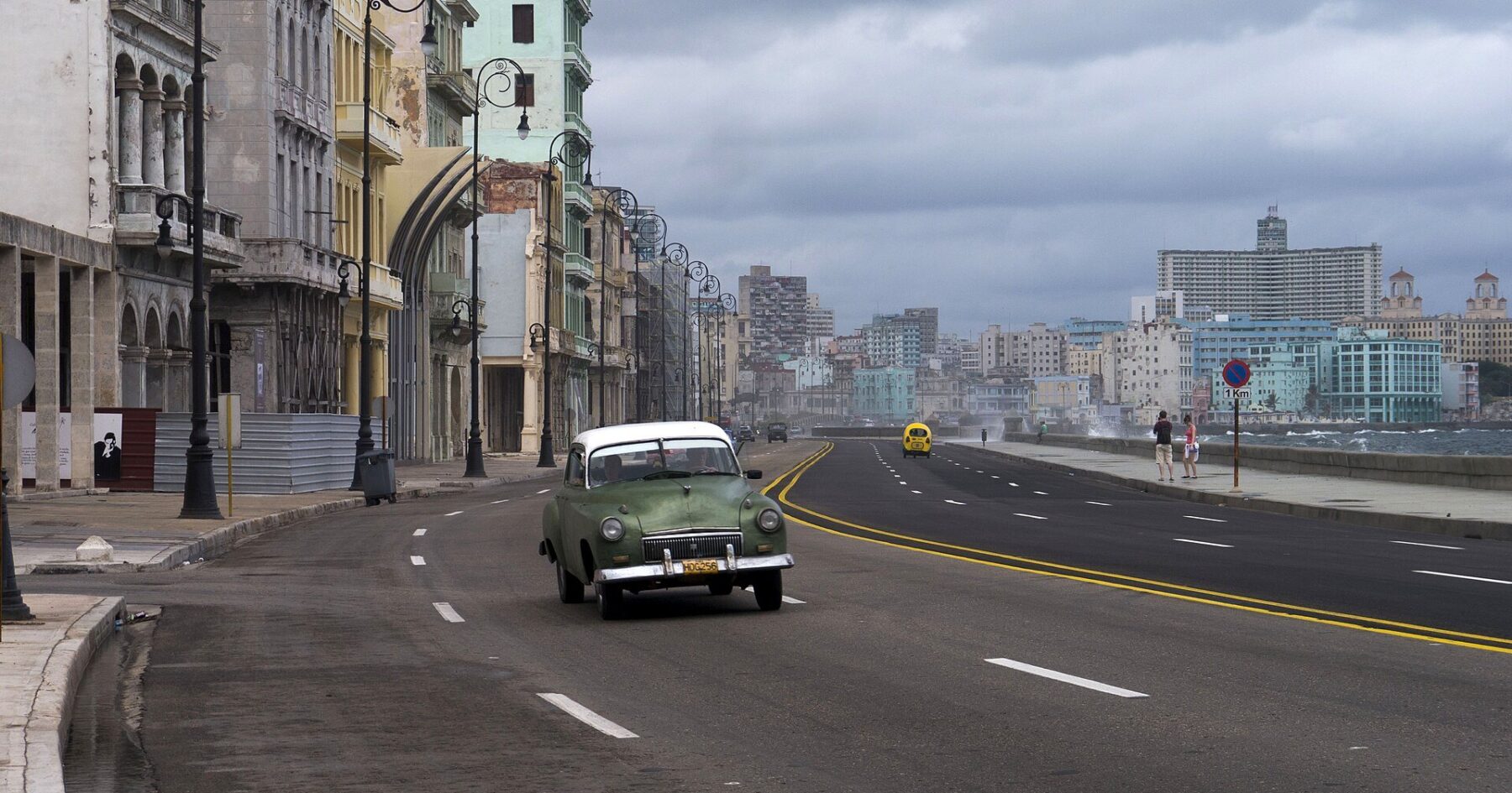 A vintage car drives along the Malecón seafront in Havana, Cuba, under a cloudy sky