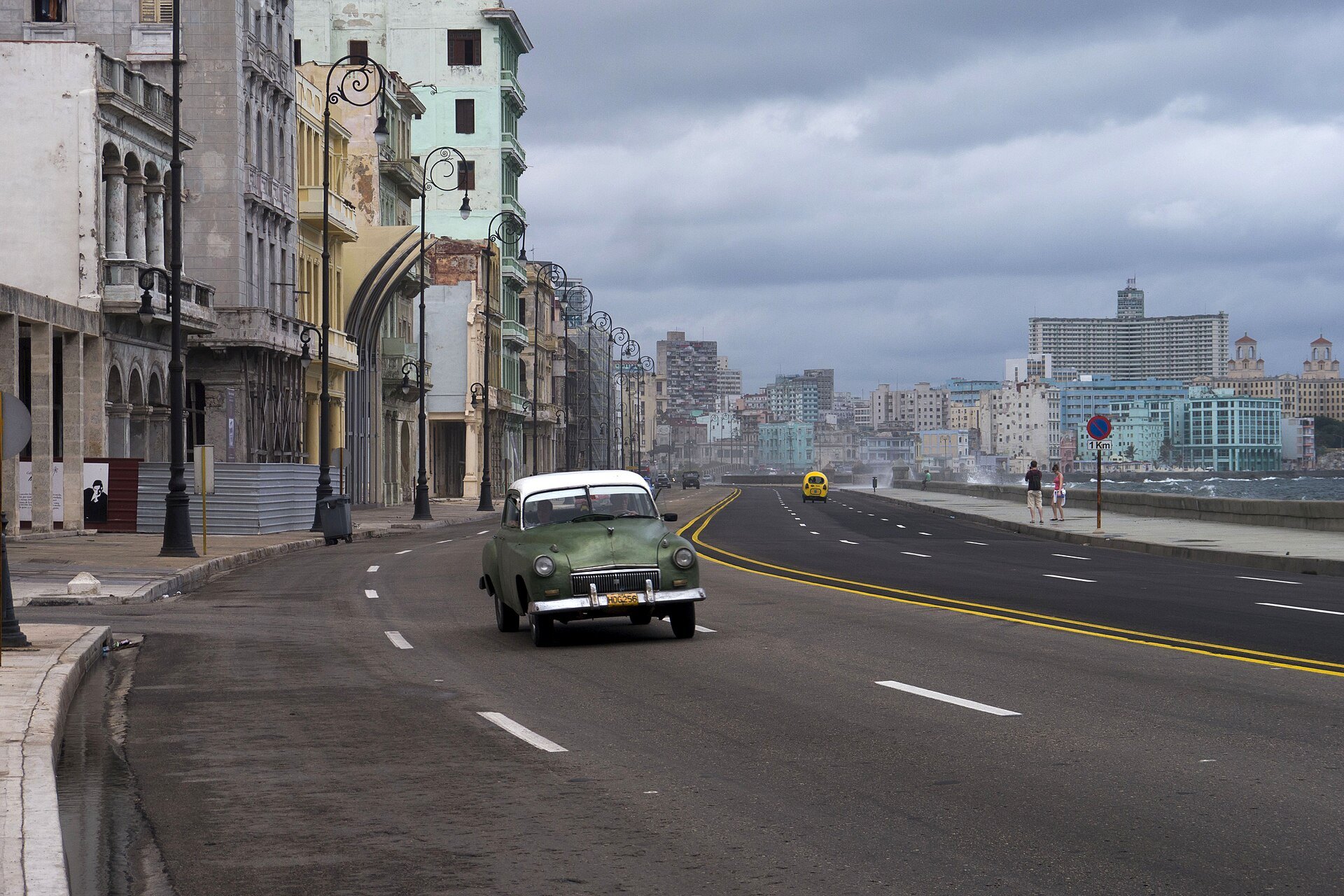 A vintage car drives along the Malecón seafront in Havana, Cuba, under a cloudy sky