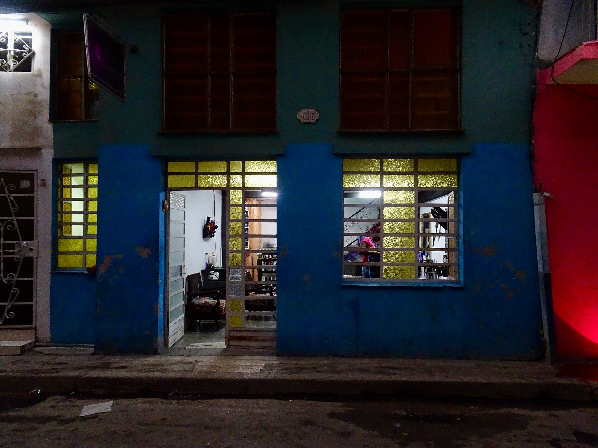 A lit ground-floor shop on a Havana street at night