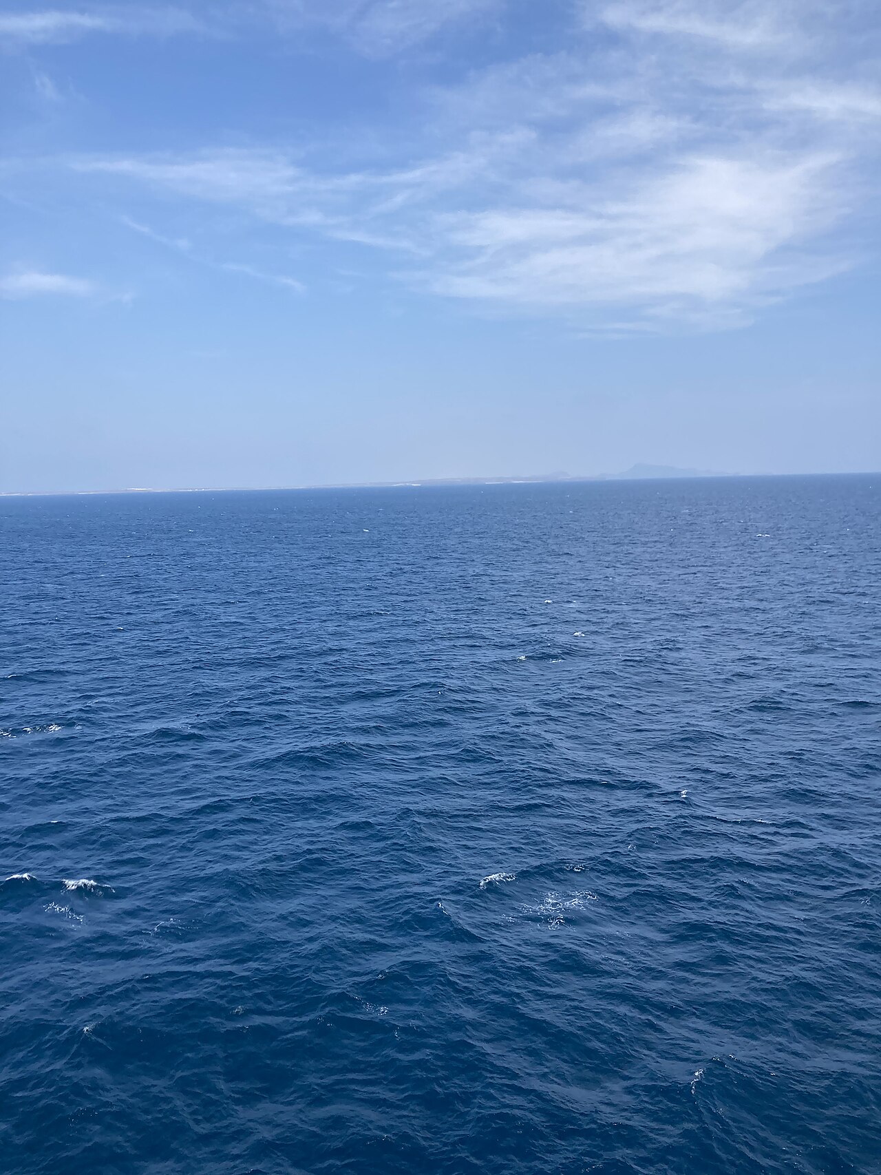 Open blue water with a faint coastline on the horizon in the Bab el-Mandeb strait