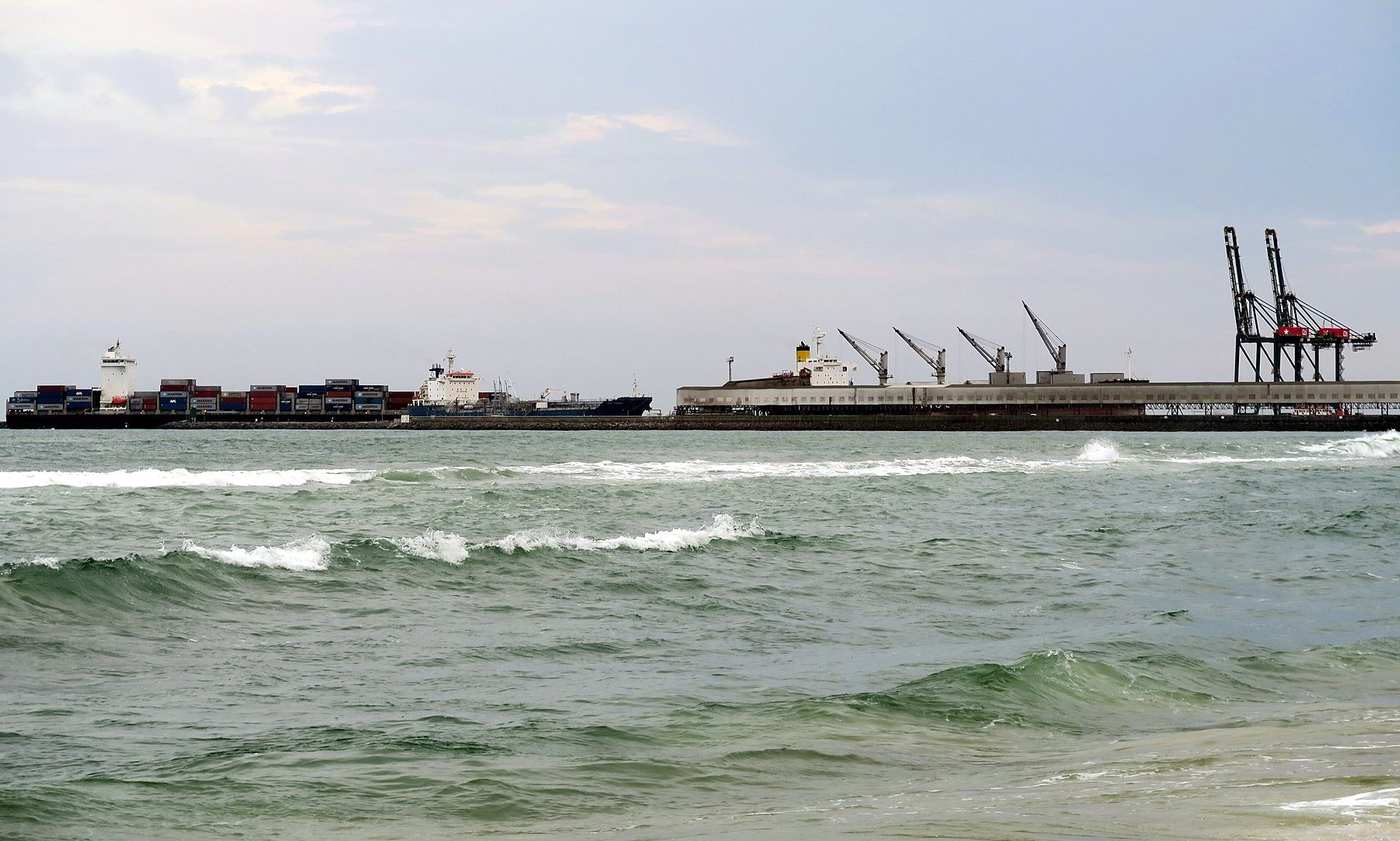 Container ships and gantry cranes at the Port of Lomé, Togo, seen from the beach