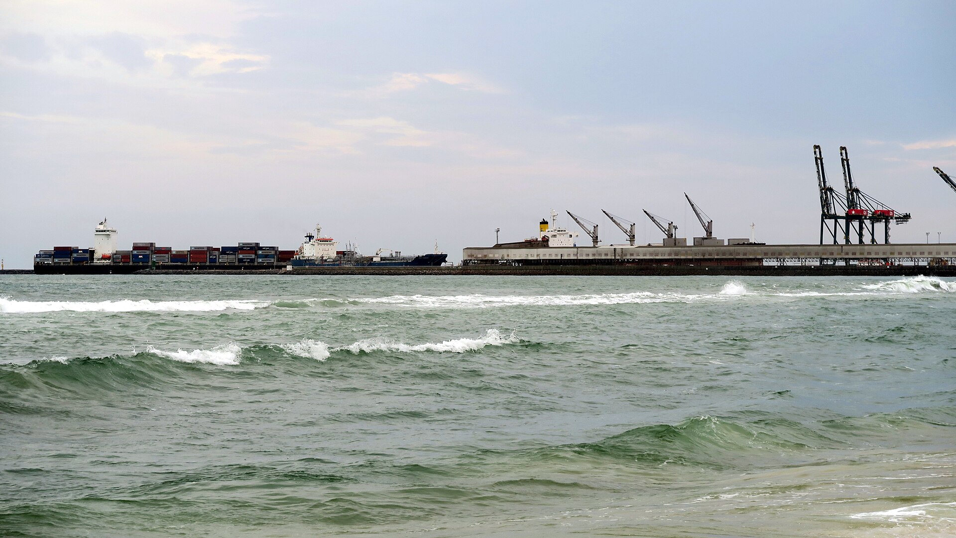 Container ships and gantry cranes at the Port of Lomé, Togo, seen from the beach