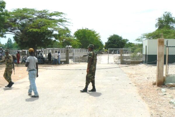 Dominican soldiers stand behind a chain across the road at the border crossing with Haiti at Pedernales, Dominican Republic