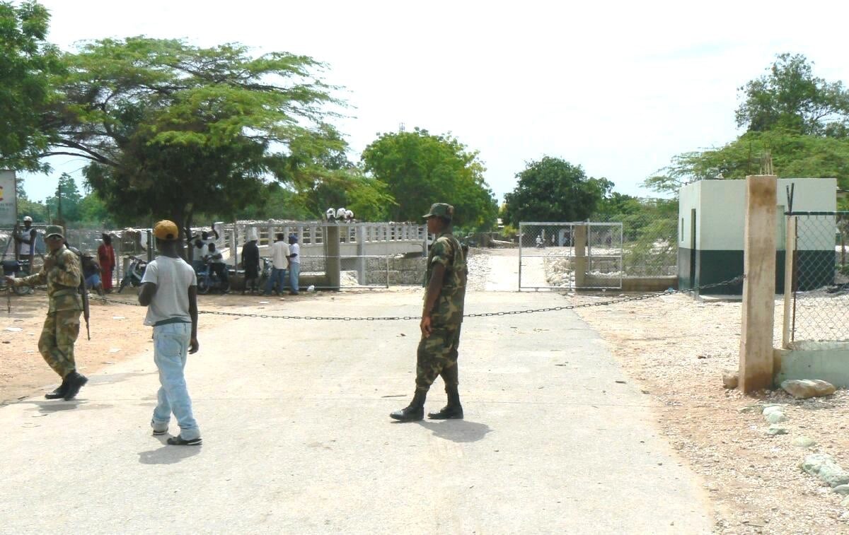 Dominican soldiers stand behind a chain across the road at the border crossing with Haiti at Pedernales, Dominican Republic
