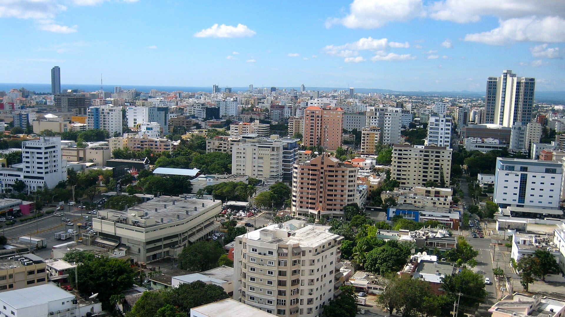 A view over the buildings of Santo Domingo with the Caribbean on the horizon under a blue sky with scattered clouds