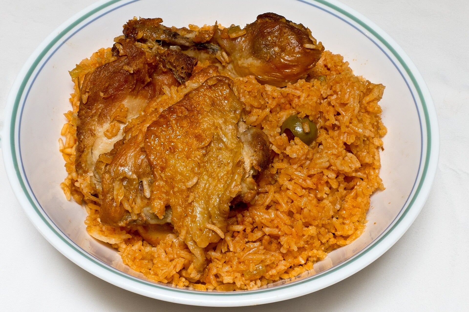 Plate of locrio de pollo, a Dominican dish of seasoned rice with fried chicken thighs and an olive