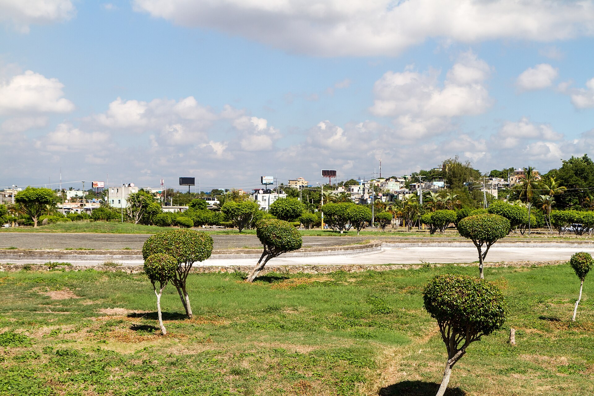 Low-rise homes and palm trees in Santo Domingo Este, Dominican Republic, under a cloudy sky