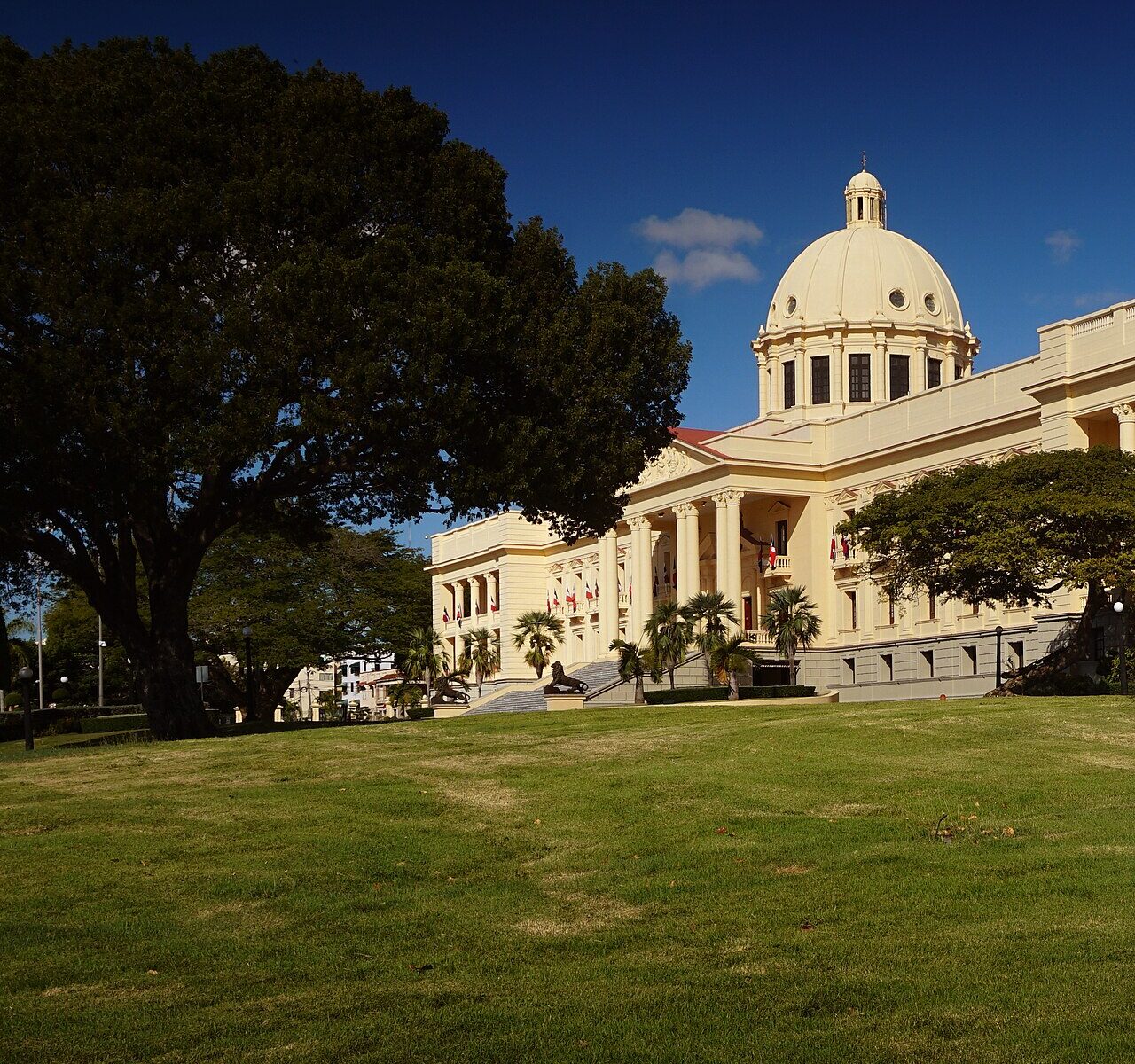 The cream-coloured National Palace in Santo Domingo with its white dome, seen across a lawn under a deep blue sky