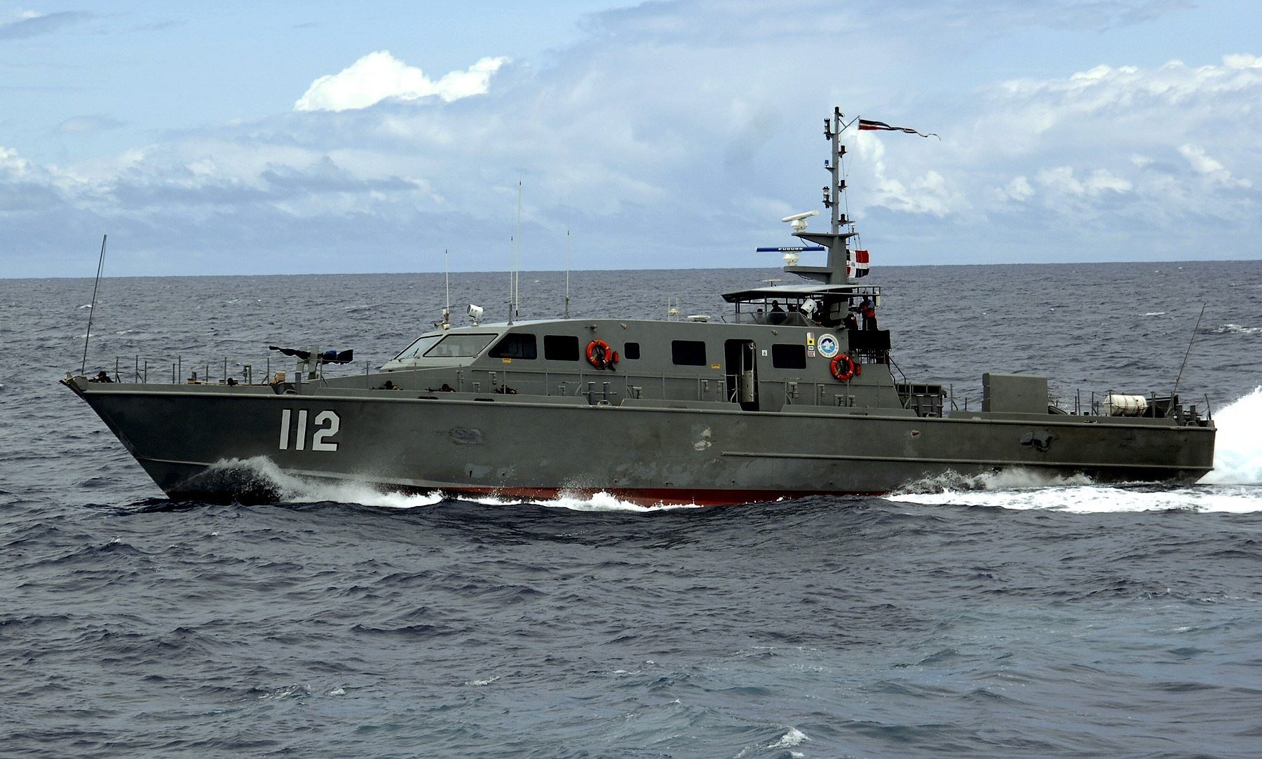 Dominican Navy patrol craft number 112 speeding through open sea under a partly cloudy sky
