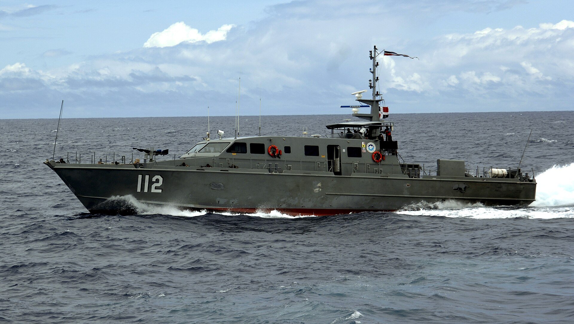 Dominican Navy patrol craft number 112 speeding through open sea under a partly cloudy sky