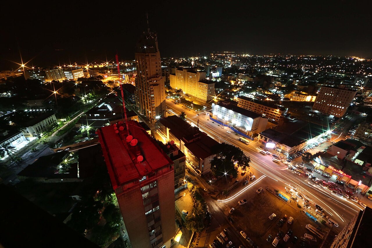 Downtown Kinshasa at night seen from a high building, with lit towers and traffic on a main boulevard