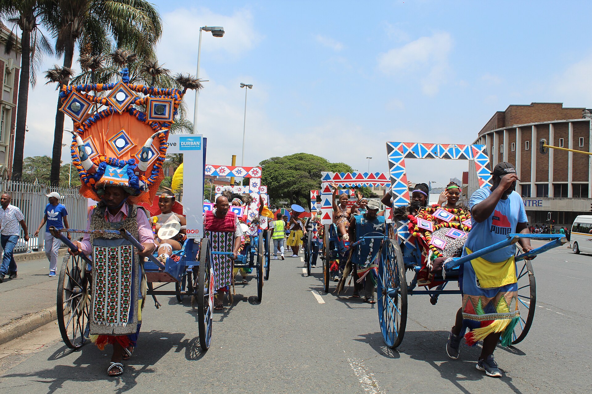 Rickshaw pullers in beaded costumes and tall headdresses lead the Indoni parade through central Durban, South Africa