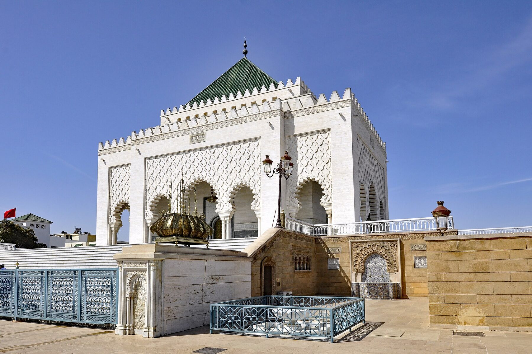 The white marble Mausoleum of Mohammed V in Rabat with its green-tiled roof under a blue sky