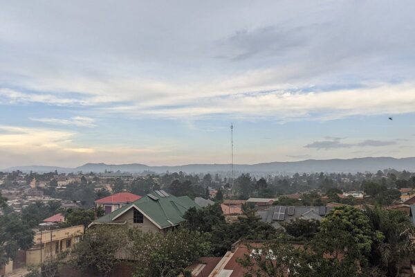 Rooftops of Bunia in Ituri province, northeast Congo, with a tall mast and hills under a dawn sky