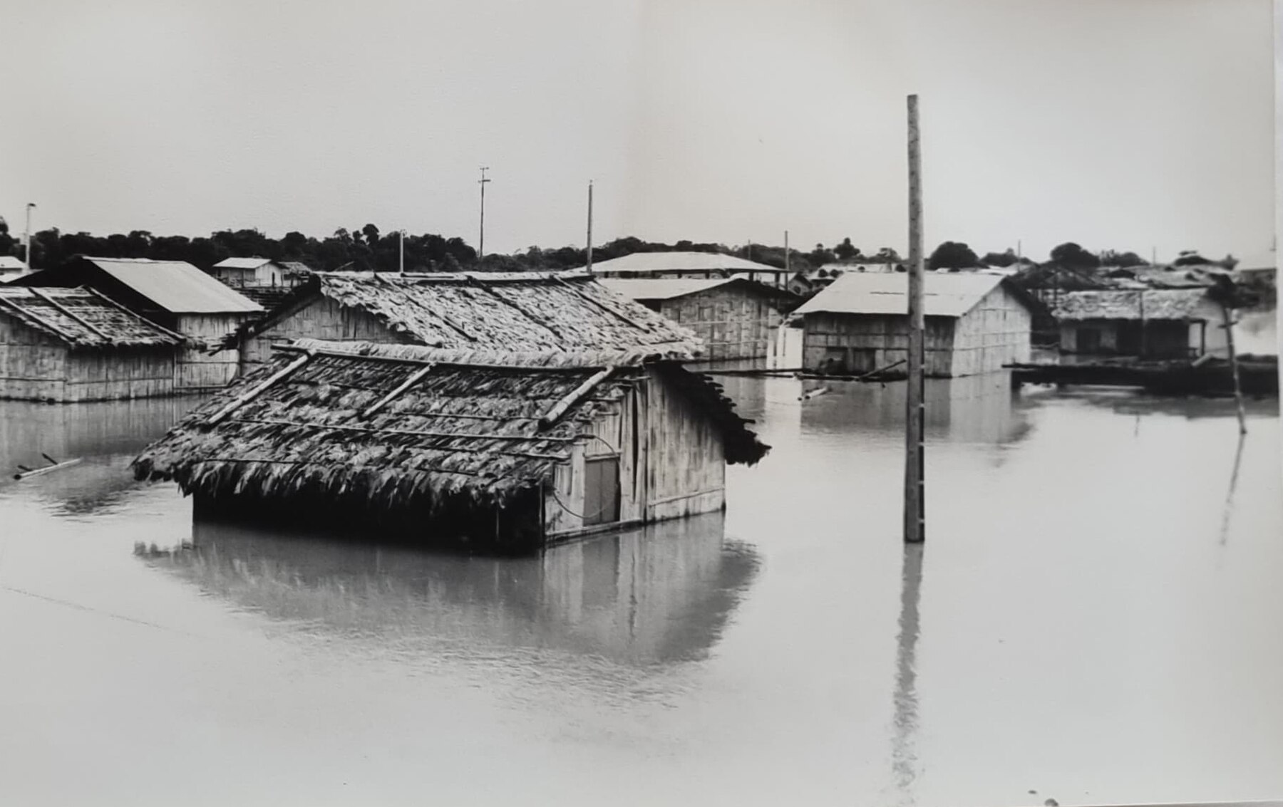 Black-and-white archive photo of flooded houses and a utility pole in Babahoyo, Ecuador, during an earlier El Niño event