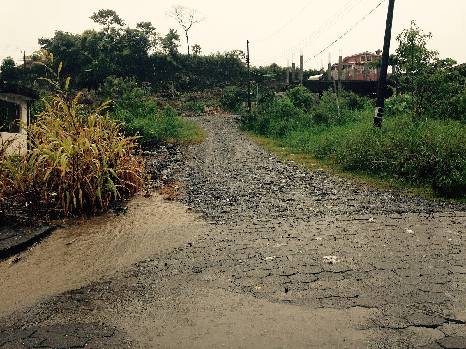 A rain-flooded gravel and cobblestone street in Puyo, Pastaza province, Ecuador