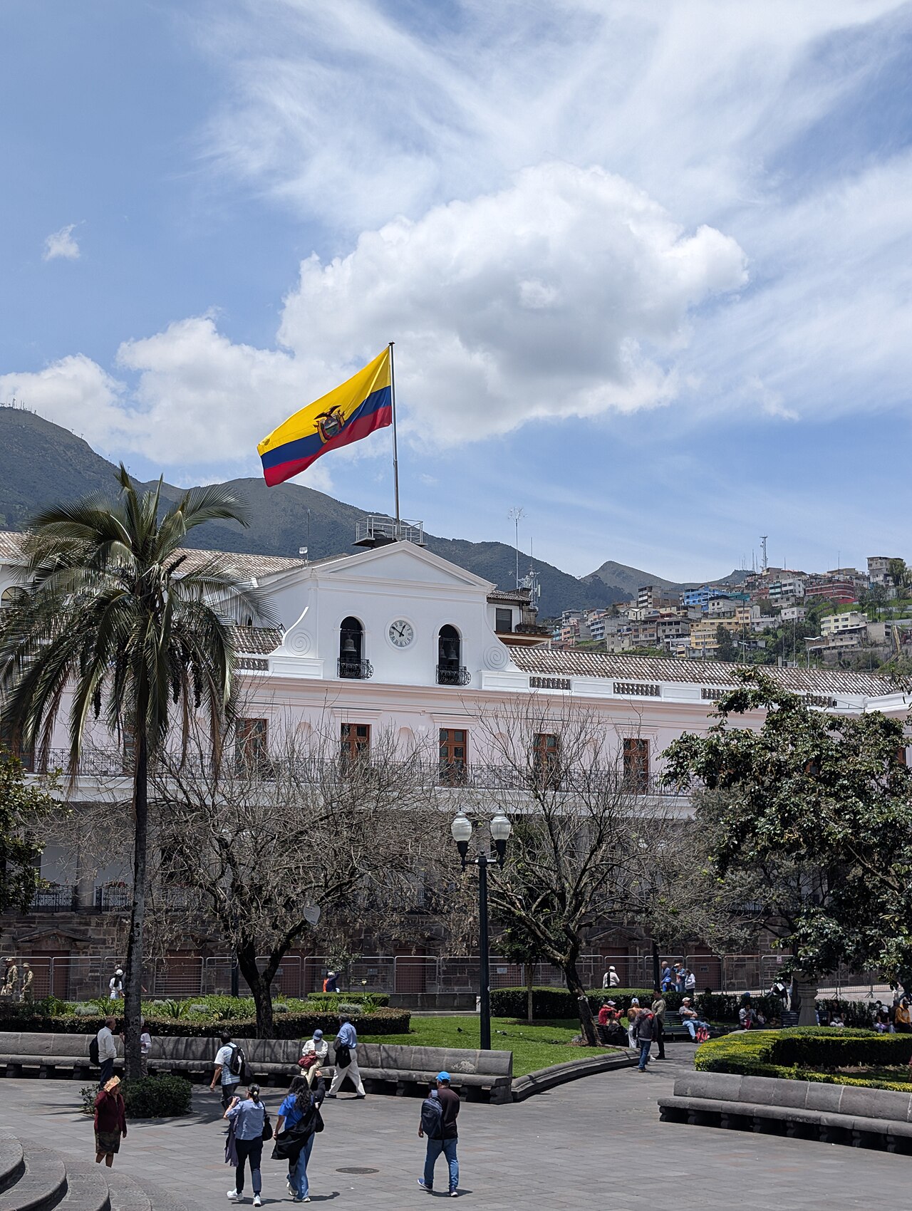 The Ecuadorian flag flying above the Carondelet Palace in Quito's Plaza Grande with the Andes hills behind