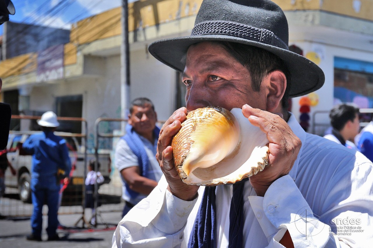A man in a black hat blows a conch shell during an Inti Raymi celebration in Imbabura province, Ecuador