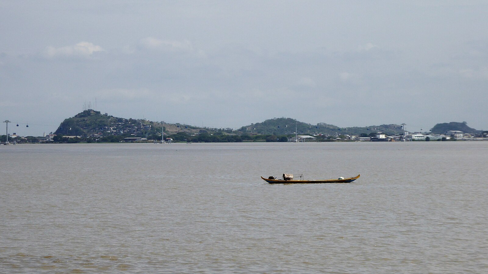 The Guayas River off Guayaquil, Ecuador, with a small boat and hills in the background