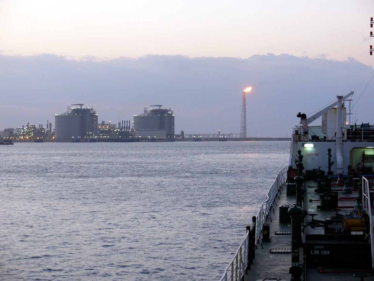 Gas and industrial plant with a flare on the coast at Damietta, Egypt, seen from a ship at dusk