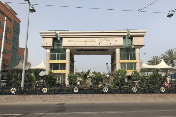 Main entrance gate of the Port of Alexandria in Egypt, a stone arch with the port name in English and Arabic