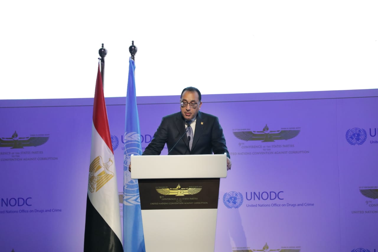 Egyptian Prime Minister Mostafa Madbouly speaking at a lectern beside the Egyptian and United Nations flags, in front of a purple UNODC backdrop
