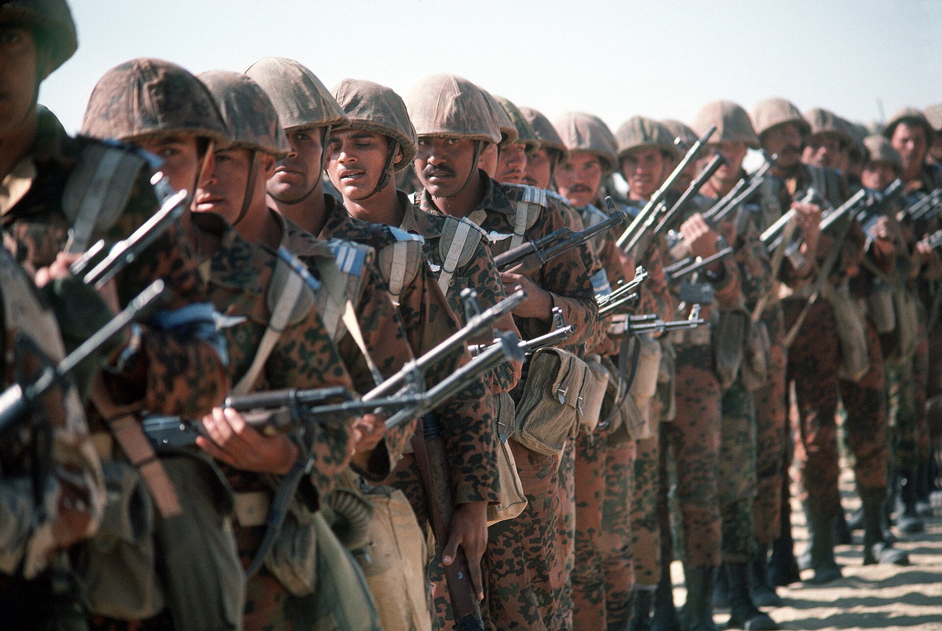 A column of Egyptian soldiers in camouflage uniforms and helmets holding rifles