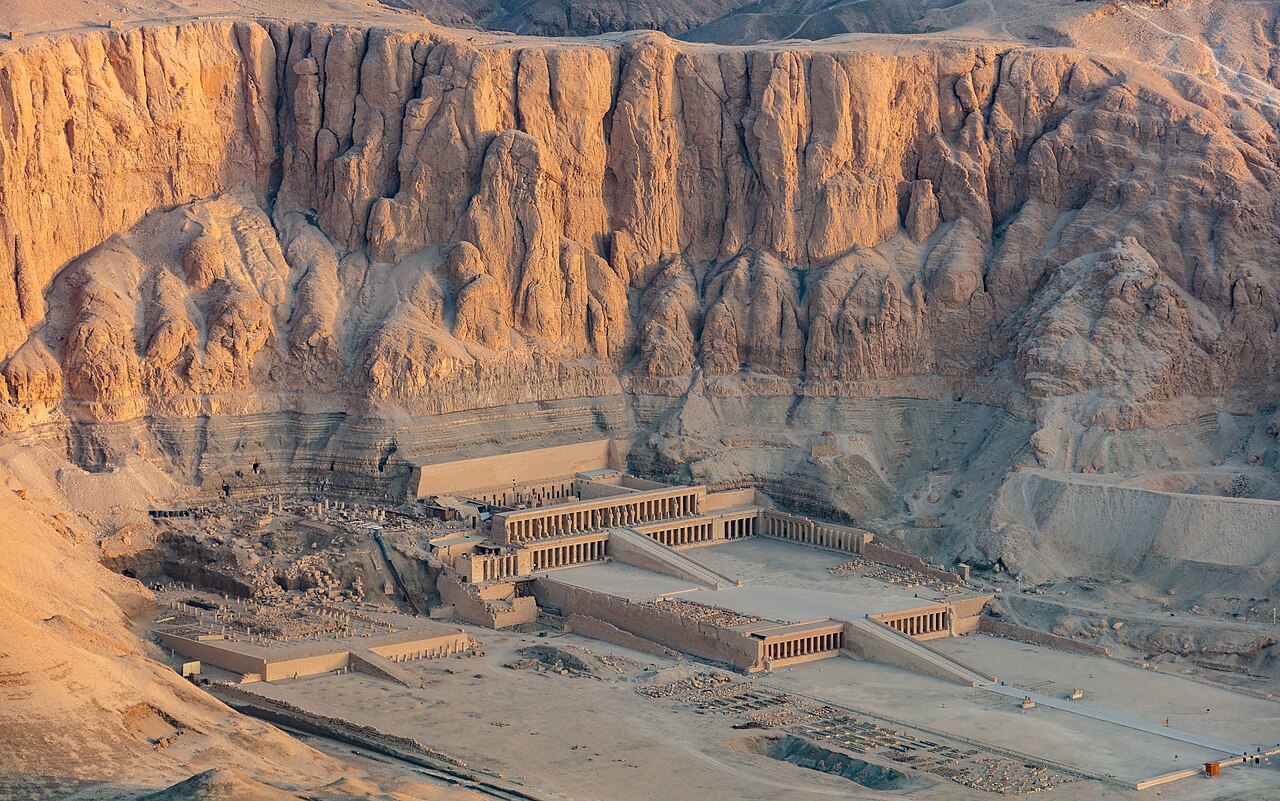 The Temple of Hatshepsut at Deir el-Bahari in Luxor, a terraced temple at the foot of tall golden cliffs in warm morning light.