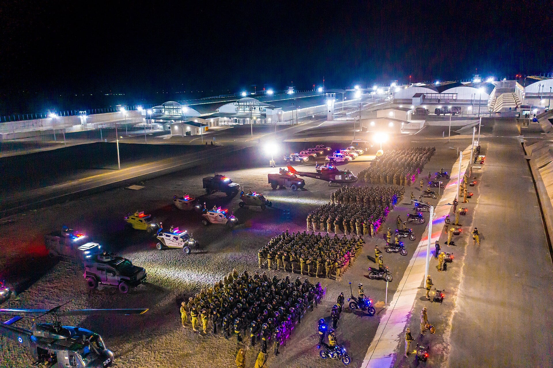 Security personnel and vehicles assembled at night outside the CECOT mega-prison in El Salvador