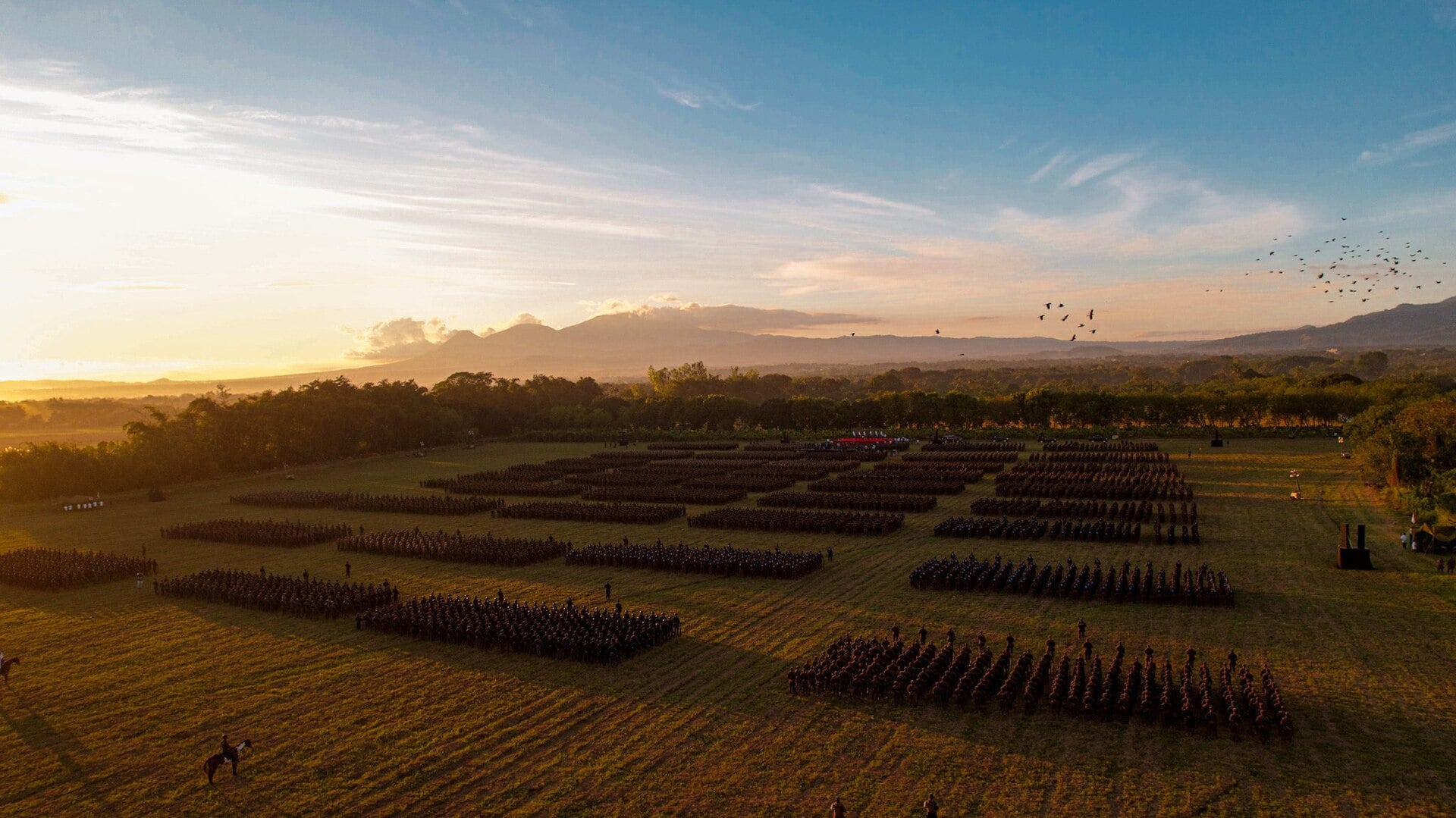 Aerial view of Salvadoran armed forces units in formation at sunset with a volcano in the background in El Salvador