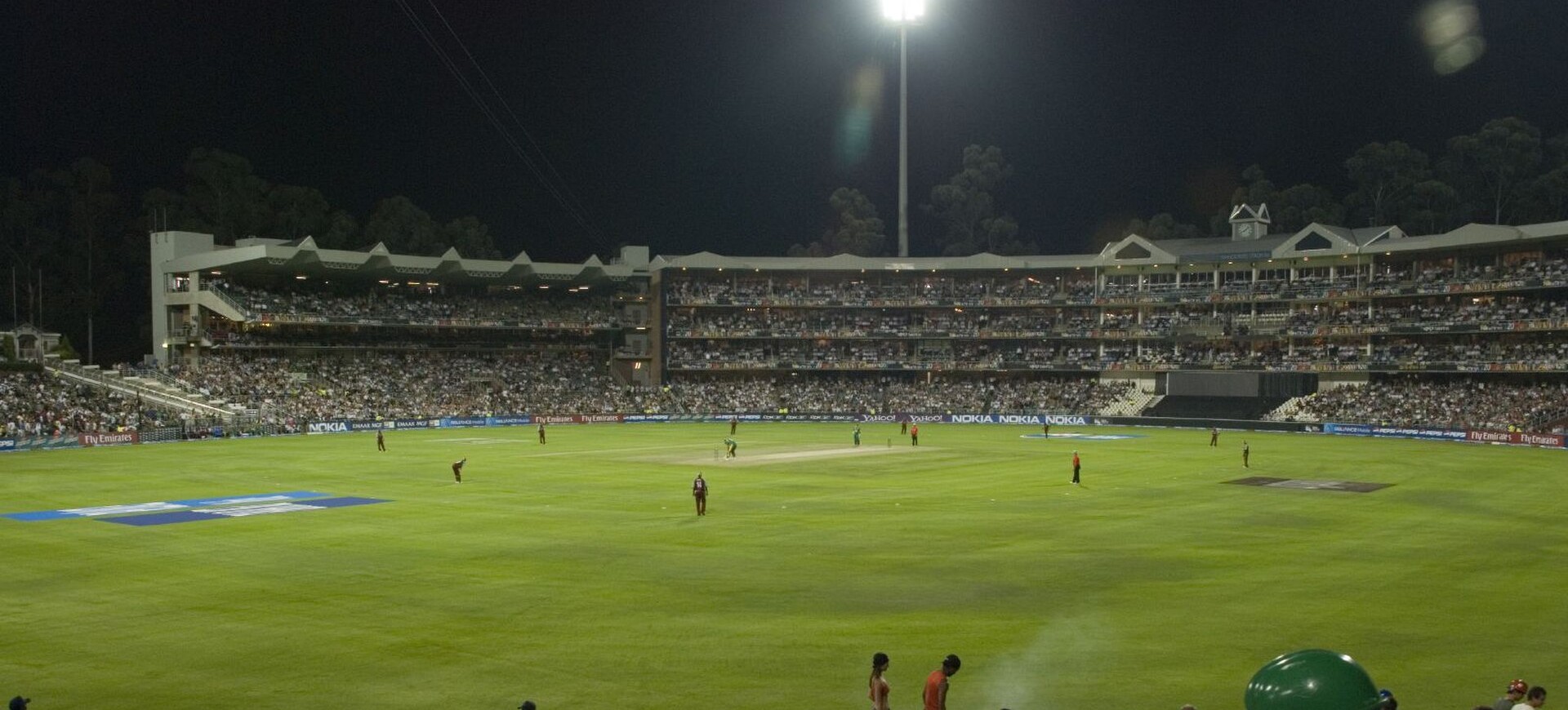 Floodlit Wanderers Stadium in Johannesburg during a cricket match, with packed stands around the field