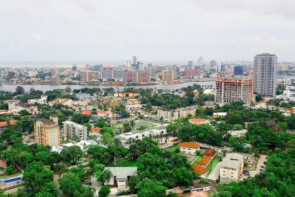 Aerial view over the Ikoyi district of Lagos toward the lagoon and the high-rises of Victoria Island under a cloudy sky.
