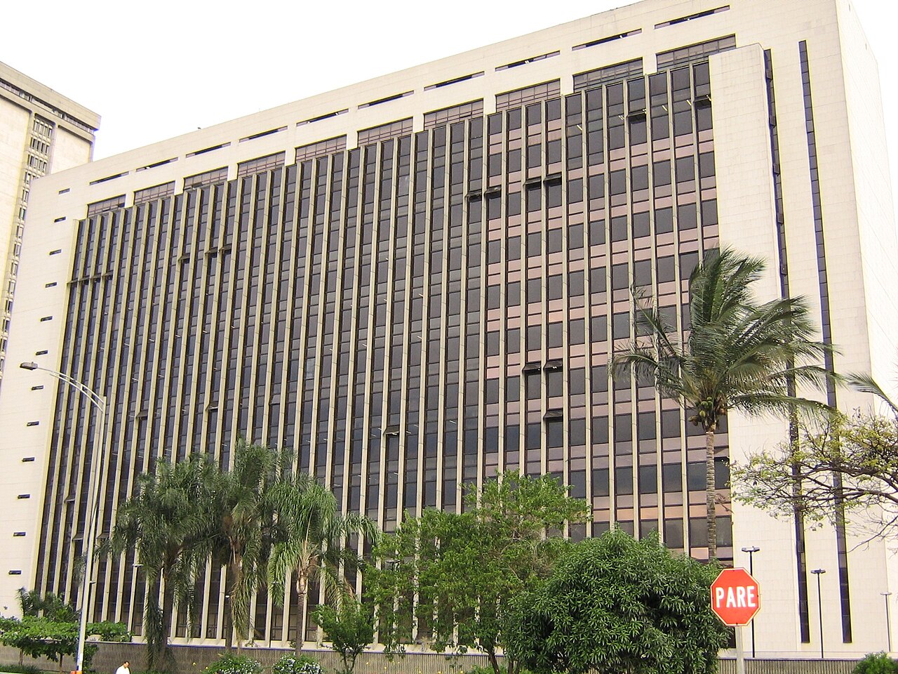 Tall office building with a dark glass facade and palm trees in front, labelled as the Alcaldía de Medellín