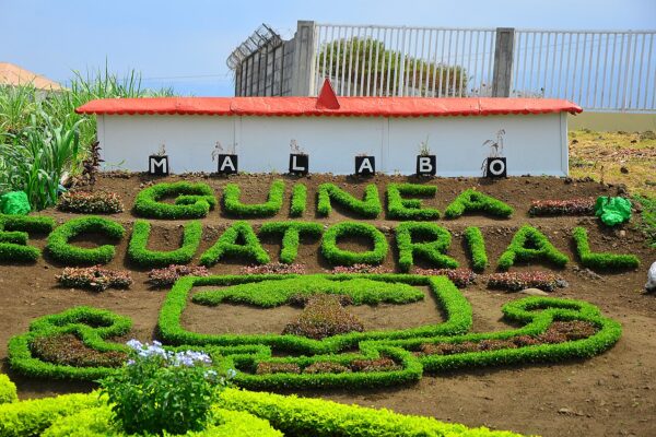 Hedges trimmed into the words Guinea Ecuatorial below the letters MALABO on a roadside bank