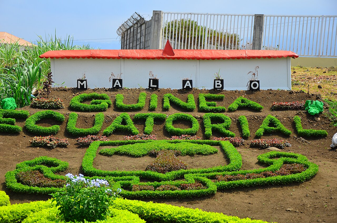 Hedges trimmed into the words Guinea Ecuatorial below the letters MALABO on a roadside bank