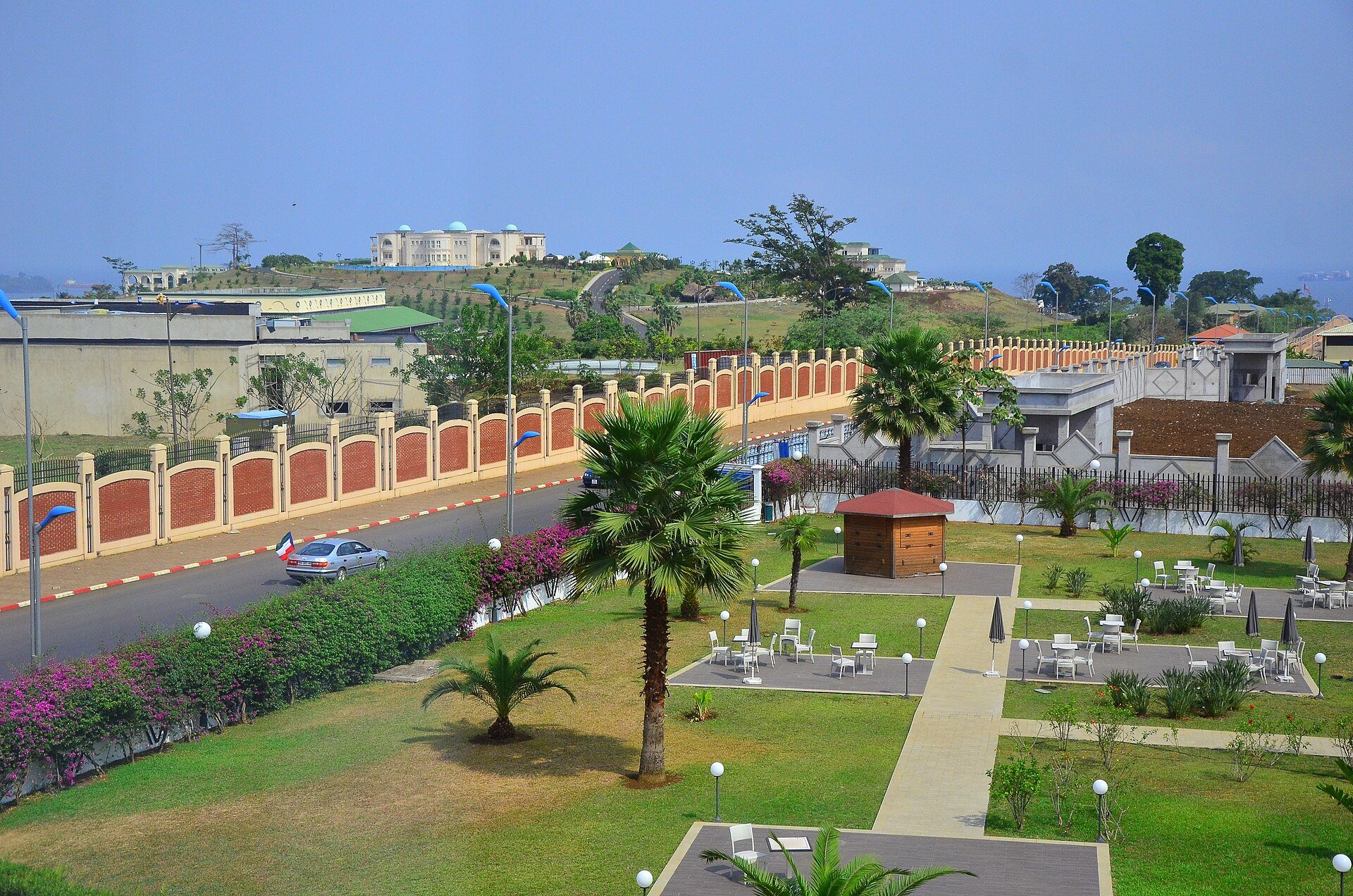 Gardens, a walled road and large buildings on a hill in Malabo, Equatorial Guinea.