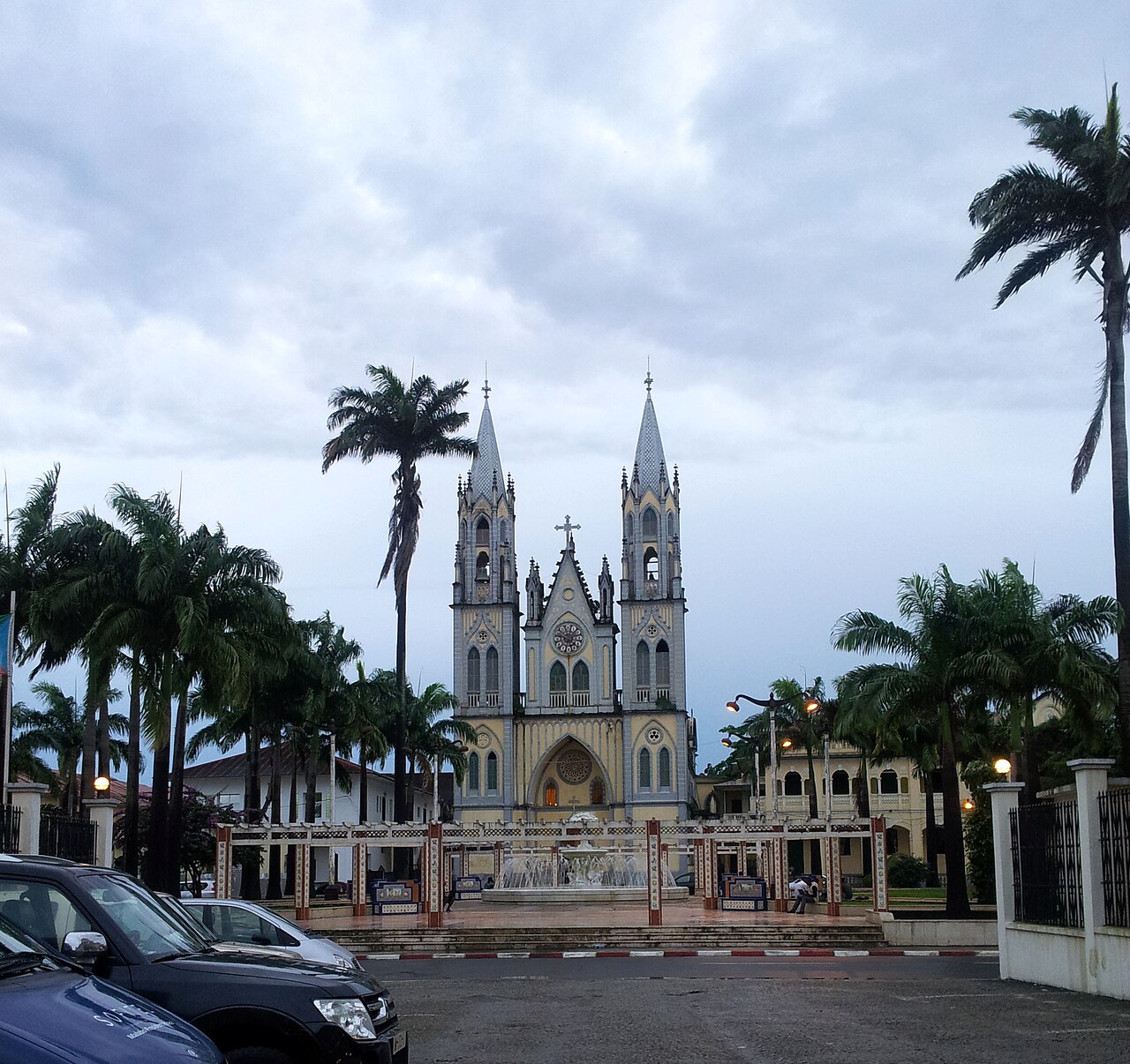 Twin-spired Santa Isabel Cathedral in Malabo behind a fountain plaza lined with palm trees