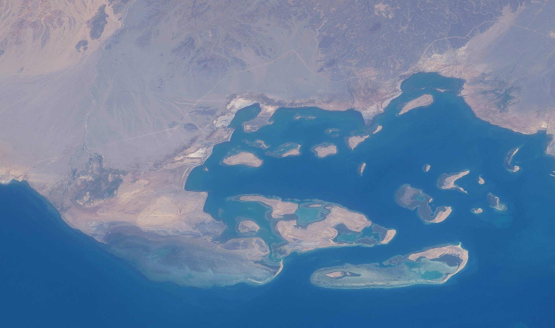 Space view of Assab Bay and offshore islands on Eritrea's Red Sea coast with deep blue water and desert shoreline